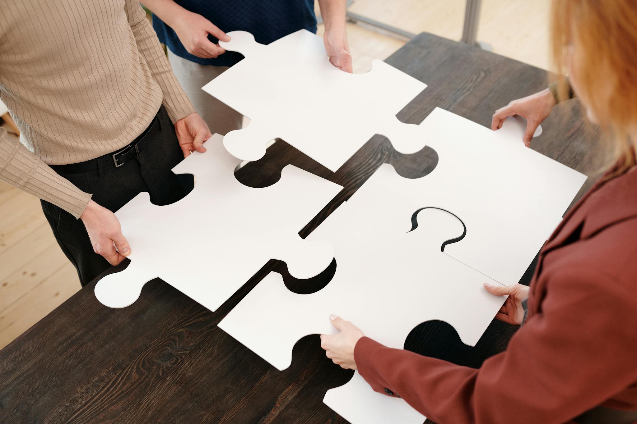 IP Services for Indian Startups 5 Four people collaborate by assembling large white puzzle pieces on a table.